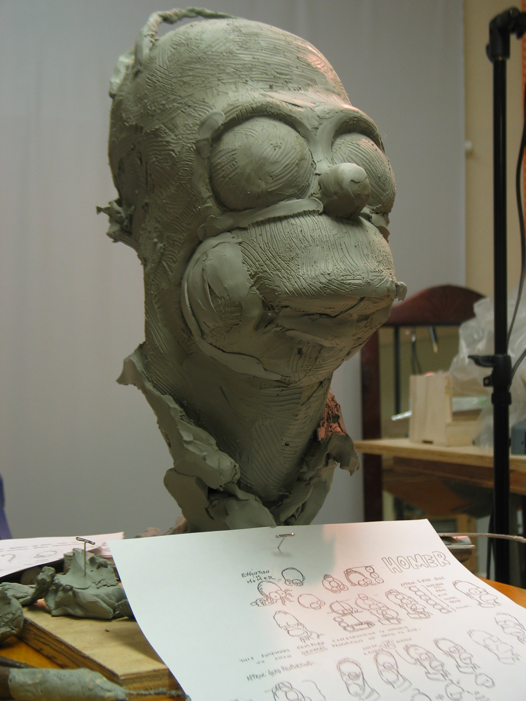 Homer Simpson bust being sculpted by Richard Becker with Simpsons Style Guide as a reference